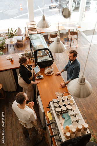 Фотография A group of White adult men and one woman interact at a cafe counter