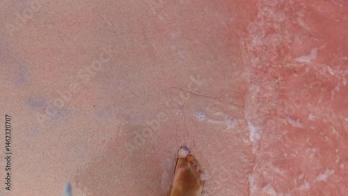 Woman's legs walking on the pink beach in Komodo island Indonesia