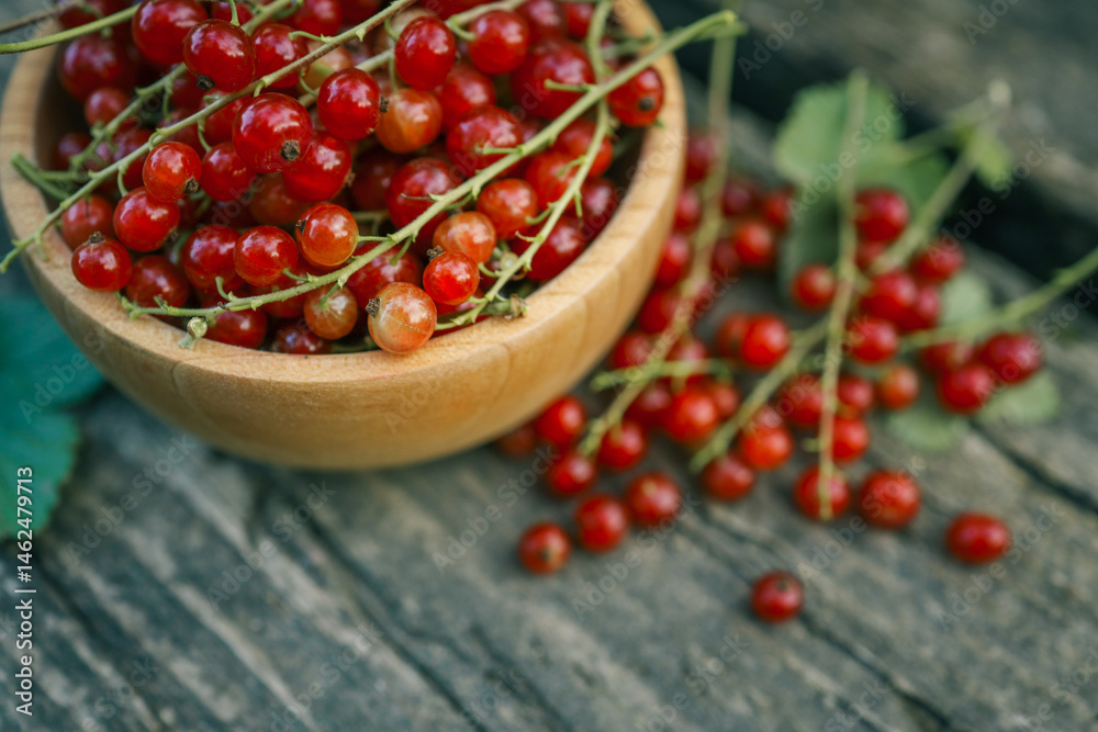 Fresh red currants in a wooden bowl on rustic wooden table. Natural summer harvest scene with vibrant red berries and green blurred background, perfect for healthy eating or gardening themes Fresh red currants in a wooden bowl on rustic wooden table. Natural summer harvest scene with vibrant red berries and green blurred background, perfect for healthy eating or gardening themes