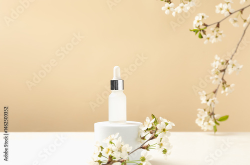 Stylish presentation of cosmetic product and twigs with beautiful flowers on beige background