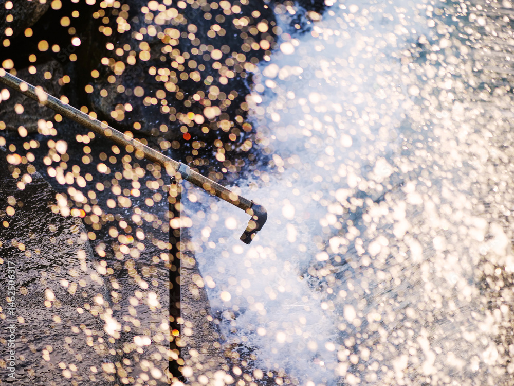 Powerful ocean wave crushes on stone stairs with metal hand rail creating splash of water. Nature energy. Selective focus. Watching water is relaxing outdoor activity.