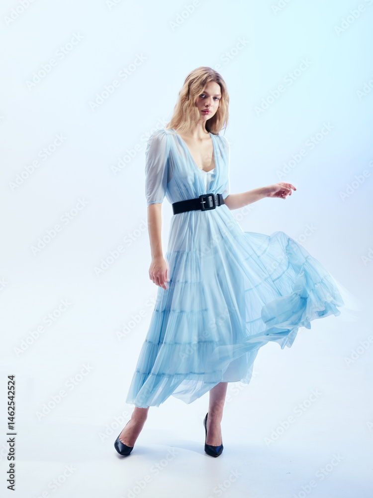 Naklejka premium Girl model in blue dress on blue studio background.