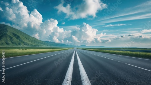 New roadway alongside green mountains under a cloudy sky in a scenic outdoor setting