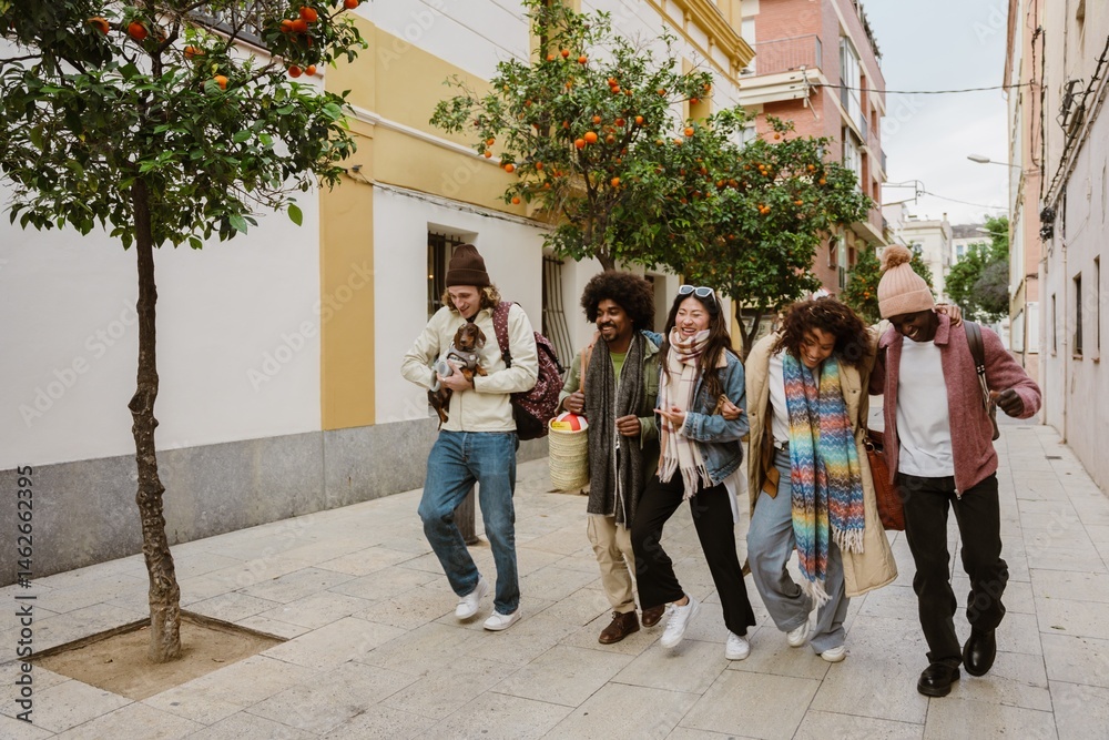 Fototapeta premium A group of four friends are walking and putting their arms around each other while a male friend walks next to them holding a dog, they are laughing, on the street
