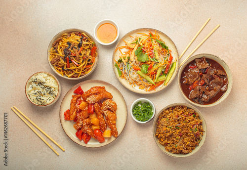 Assorted Chinese dishes, sweet and sour chicken, beef in sauce, noodles, fried rice, salad and wooden chopsticks. Chinese or Asian restaurant concept
