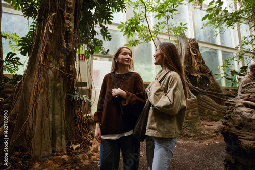 Obraz na płótnie Two female friends smiling and talking, in a botanical garden w salonie