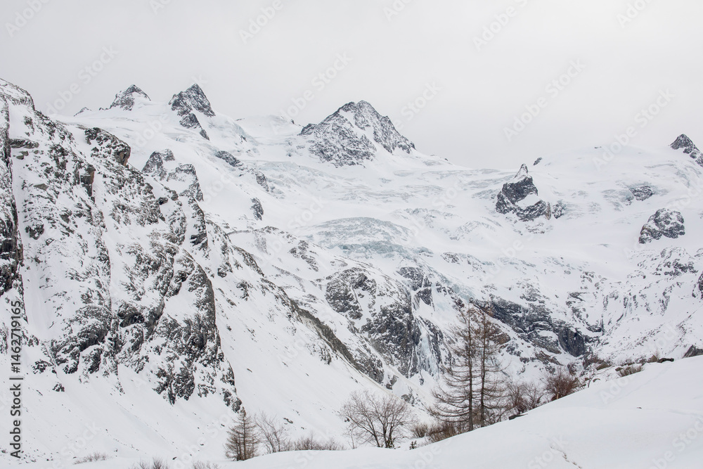 Obraz premium View of the Graubünden mountains Piz Roseg and Pia Bernina in the Roseg Valley in winter. Snow covered landscape. Swiss Mountains.