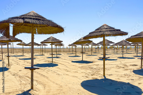 Fototapeta Naklejka Na Ścianę i Meble -  spiaggia con ombrelloni di paglia e sabbia, beach with straw umbrellas and sand