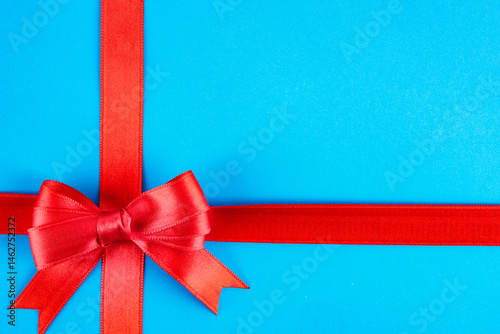 Obraz na płótnie Red ribbon and bow on blue background w salonie