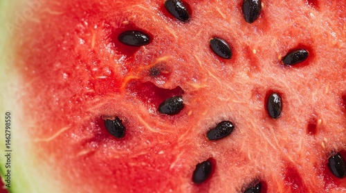 A cross-section of a watermelon with seeds Macro shot of a watermelon slice, highlighting the tiny black seeds scattered across the bright red flesh.