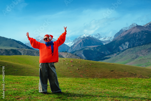 Young happy stylish woman in orange sweater dancing in the mountains photo