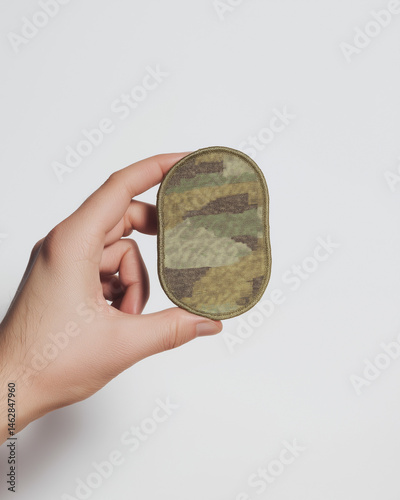 Hand holding a military camouflage patch symbolizing service and sacrifice for Veterans Day (USA) and copy space