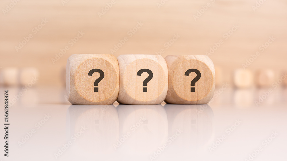 Three wooden cubes with question marks on smooth surface with blurred background Three wooden cubes with question marks on smooth surface with blurred background