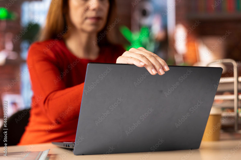 Smiling female freelancer browsing the web on her laptop in a modern apartment, demonstrating a lifestyle of independence, connection and productivity in a virtual workspace. Woman multitasking.