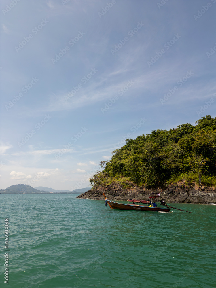 Drone shot of tropical beach and panoramic forest with exotic palm trees and blue sky, coastal scenery featuring tall coconut trees on a sunny shoreline. Tranquil seashore in Thailand, drone shot.