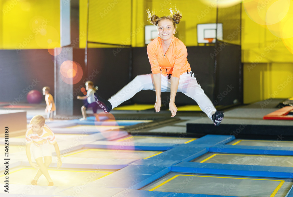 Obraz premium Playful girl jumping on trampoline at playground indoor