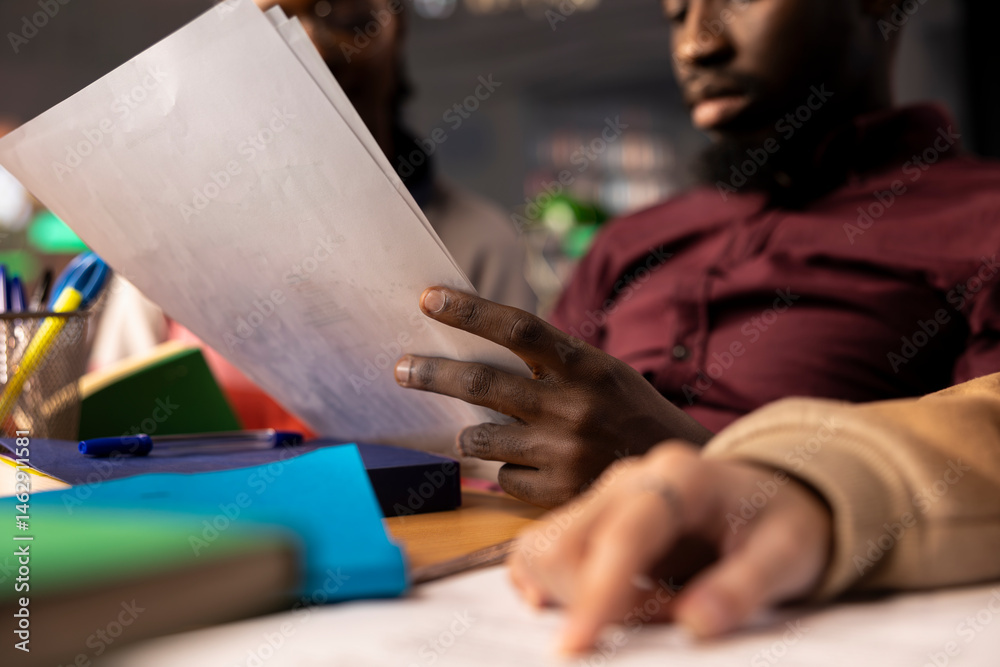 Young diverse adults in a campus library brainstorming ideas for a startup, enhancing their knowledge of business administration and corporate strategies to work on a class project. Close up.