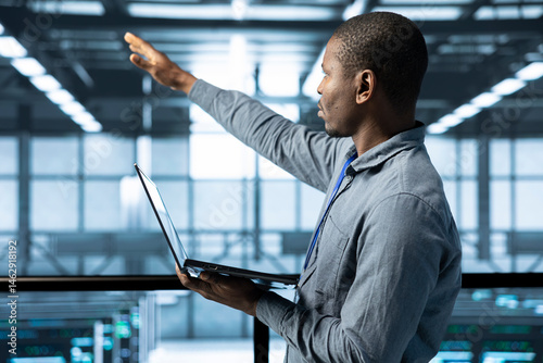 Obraz na płótnie Technician holding laptop, looking around data center, managing server virtualization, finetuning network protocols, verifying high availability configurations, enforcing advanced security measures w salonie