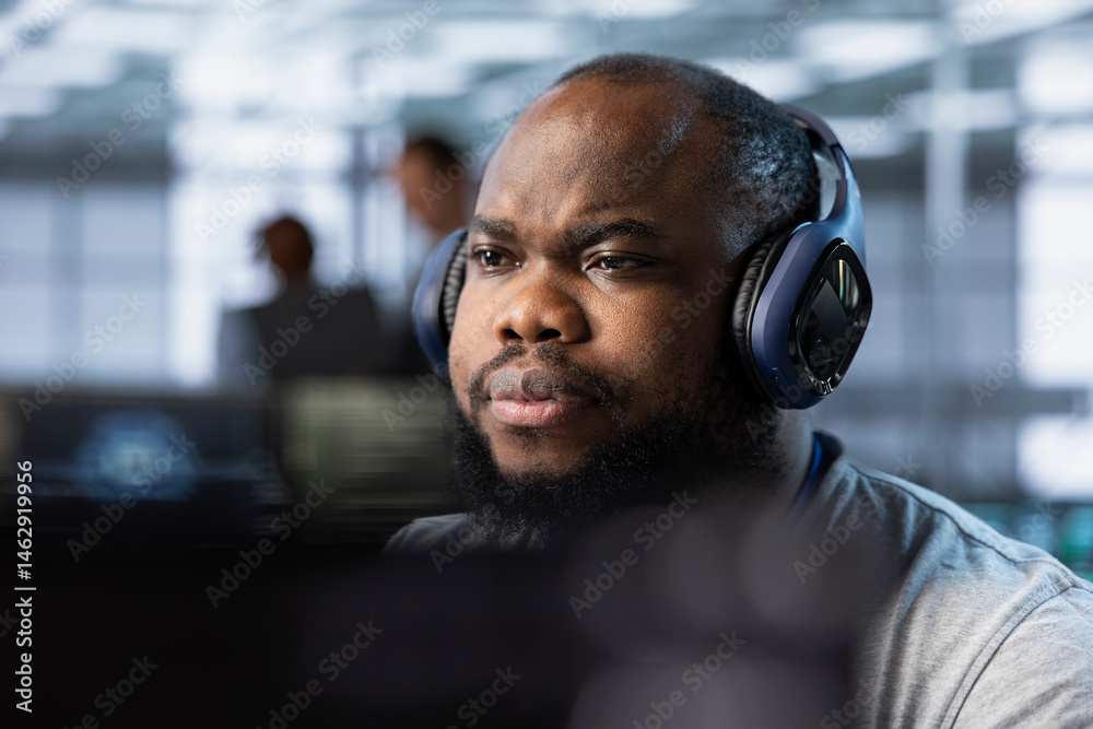 African american admin wearing headphones implementing cybersecurity measures to protect data center. Server hub worker listening music, analyzing metrics to enhance operational effectiveness