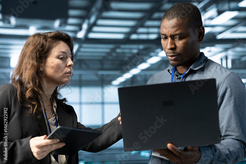 Obraz na płótnie System administrators using laptop in data center, managing server virtualization. IT specialists using notebook in server room, sustaining long term infrastructure reliability w salonie