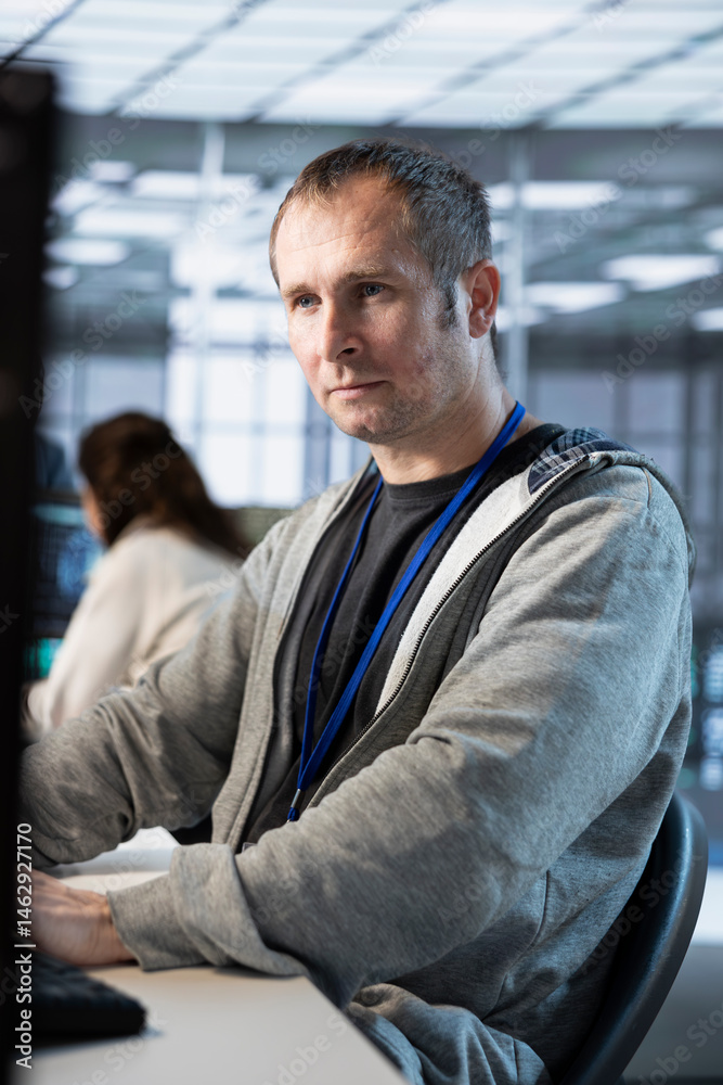 Computer scientist in server farm ensuring compliance with industry standards and regulatory requirements. Data center worker using PC, conducting security audits to protect against cyberthreats