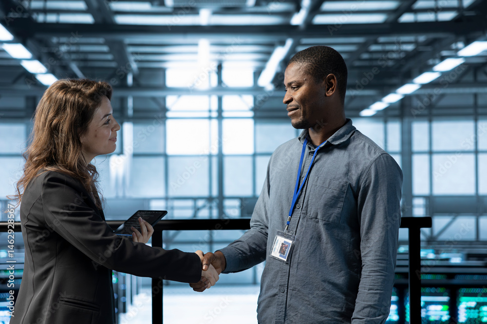 Data center system administrators meeting with inspector arriving in workplace to review equipment. IT specialist doing handshake with supervisor overseeing server farm infrastructure