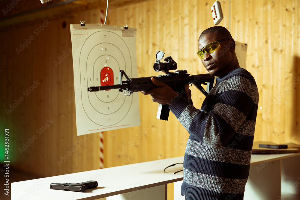 Portrait of shooting gallery client doing training, learning proper semiautomatic weapons holding etiquette. Person practicing with rifle, wearing safety eyewear to prevent injury