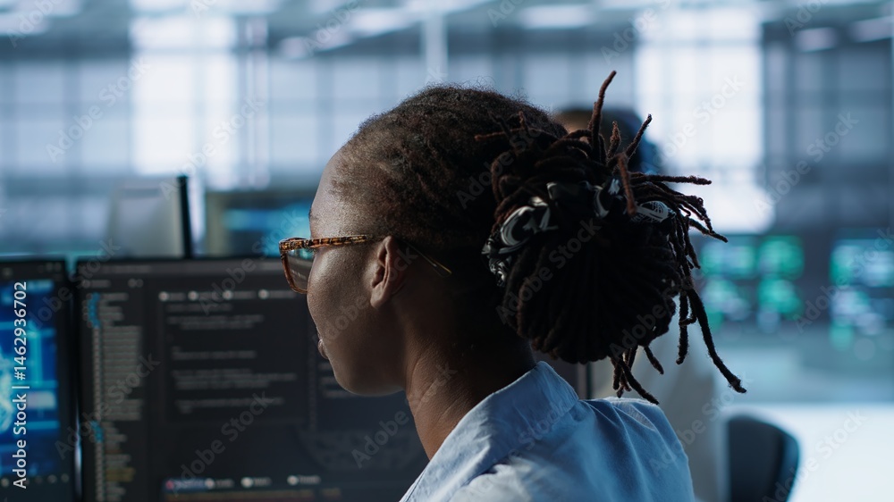 Woman programming in AI data center housing advanced equipment used for machine learning training. African american admin running code to upgrade artificial intelligence tech, camera A close up
