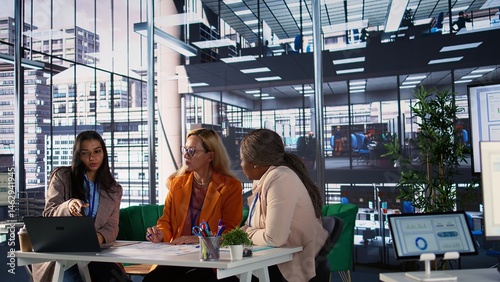 Obraz na płótnie Diverse business experts sharing ideas for corporate growth planning, analyzing infographics for monthly report task. Powerful women working together to ensure organizational productivity. Camera B. w salonie