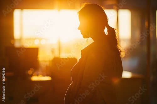 Silhouette of a pregnant woman bathed in golden light, radiating hopeful warmth.