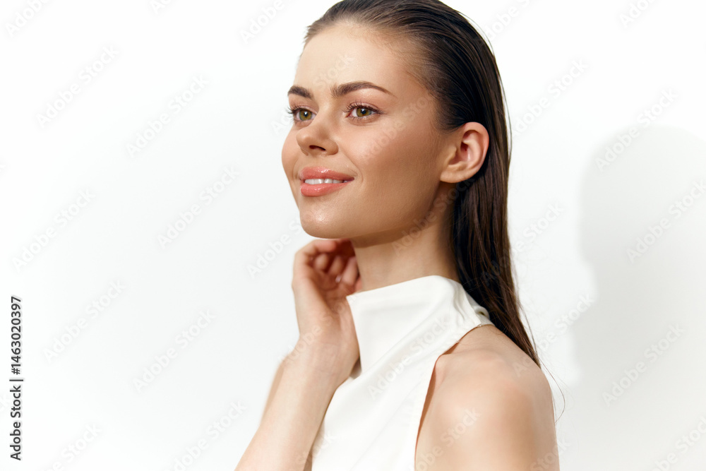 Young woman with wet hair smiling, wearing a white sleeveless top, showcasing natural beauty in a clean, bright setting.