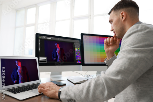 Designer working on different computers at table in office