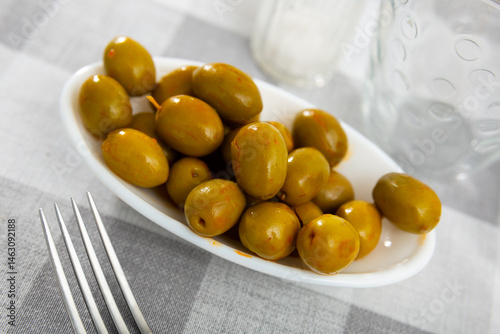Fototapeta Naklejka Na Ścianę i Meble -  Closeup of plate of pickled green olives with a stone, spanish appetizer