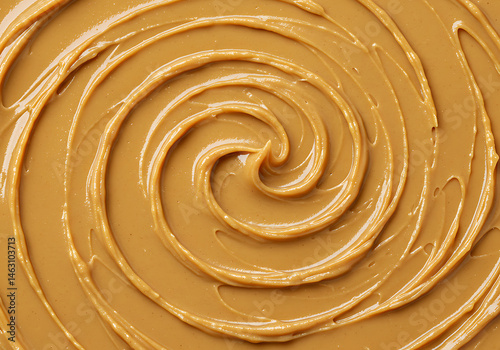 A close up shot showcasing a swirl of smooth caramel colored peanut butter filling the entire frame