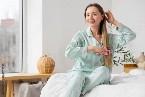 Young woman combing her hai...