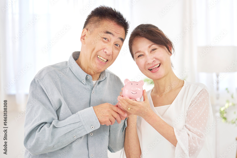 Fototapeta premium 貯金箱を持つシニア夫婦 リビング