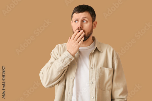 Shocked young man on beige ...