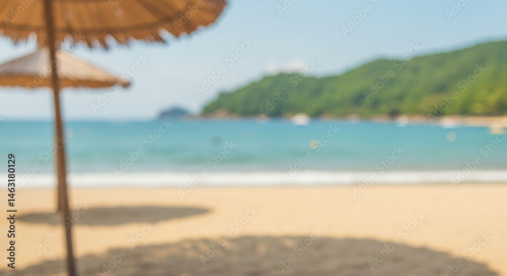 Fototapeta premium Blurred tropical beach scene with straw umbrella, golden sand, and turquoise sea. Summer vacation concept. Defocused background for relaxation and travel advertisement.