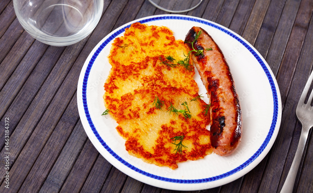 Portion of potato pancakes with roasted sausage served on plate. Portion of potato pancakes with roasted sausage served on plate.