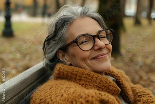 Happy Senior Woman Relaxing on a Park Bench in Autumn