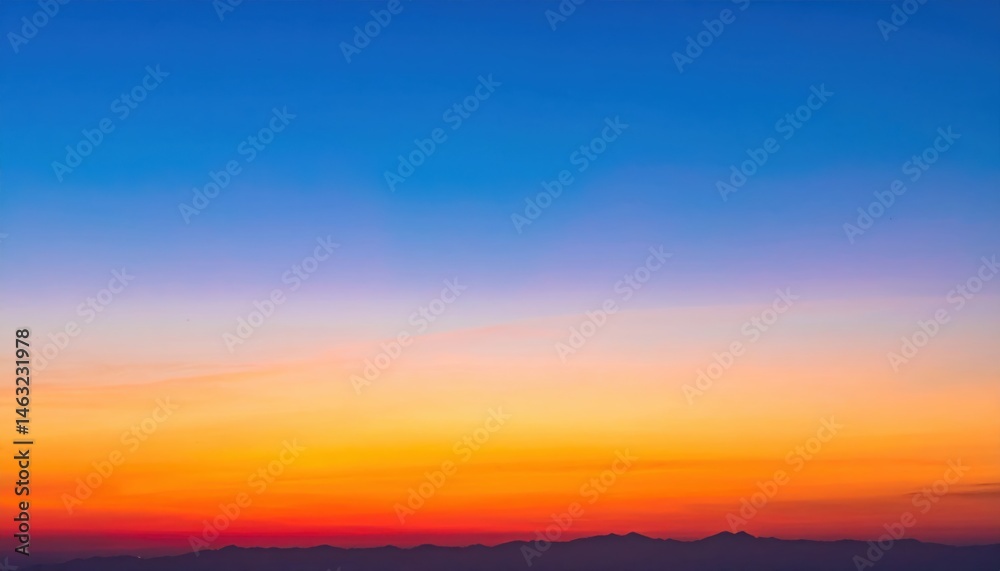 Obraz premium A stunning sunset painting the sky in vibrant hues of orange, pink, and blue, with silhouettes of distant mountains on the horizon