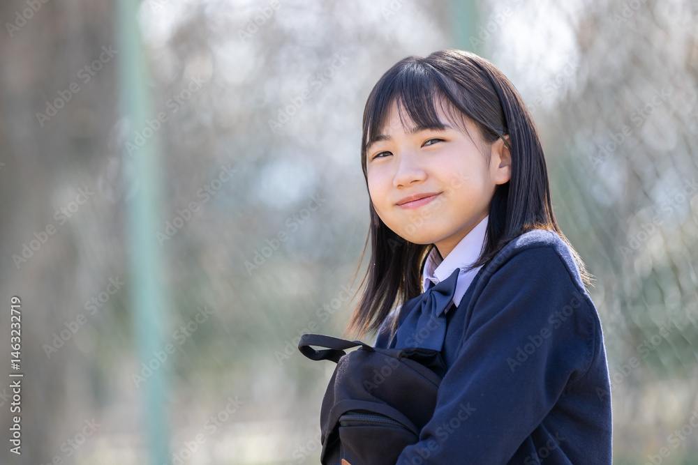 グラウンドのベンチに座る女子学生