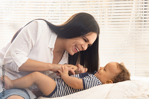 baby and young mother playing and smiling in a brightly lit room
