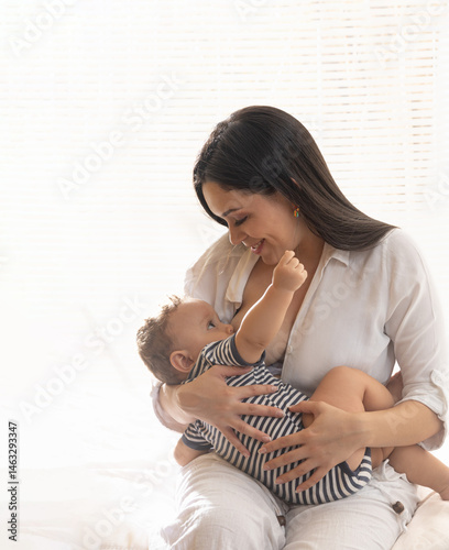 Young mother with long hair breastfeeding her 8-month-old baby, maternal connection