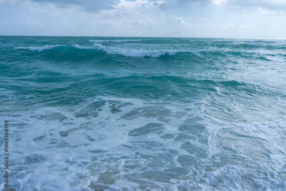 Turquoise sea water wave motion. Summer beach. Calm sea. Luxury seaside resort. Bright sky and waves on beach. Beautiful foamy shoreline. Sea background. Blue ocean. Sandy ocean beach. Sea waves.