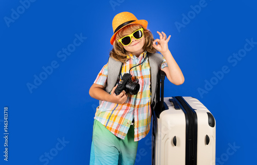 Traveler tourist kid boy 7-8 years old on isolated studio background. Travel on weekends getaway. Independent kid boy with big travel bag.