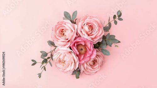 Elegant arrangement of soft pink roses and eucalyptus leaves against a simple light pink background