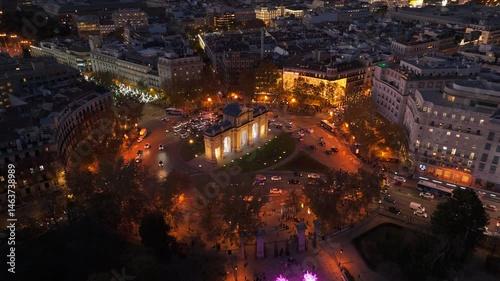 Aerial footage captures Puerta de Alcala in Madrid, showcasing vibrant city lights and twilights beauty as darkness envelops the cityscape, highlighting its rich history and lively atmosphere