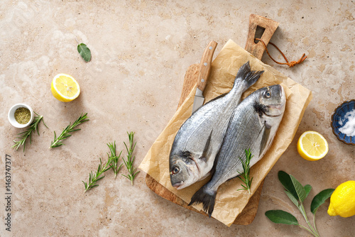 Photography Fresh raw sea bream fish or dorado fish with lemon and herbs, top view