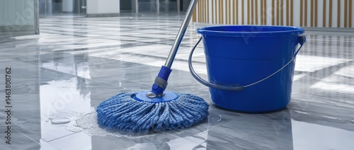 Blue mop and bucket on shiny marble floor.